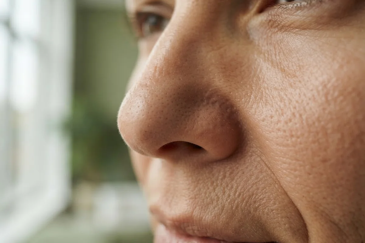 Close-up of adult nose and cheek skin texture with visible pores in soft daylight, Irvine CA